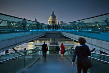 LONDON - MARCH 12 2014: People descending from the London Millennium Footbridge against the dome of Saint Paul's Cathedral at night.