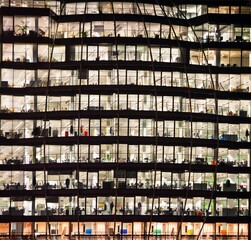 Lights on in the office building in a skyscraper at night in London.