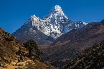 Indrukwekkende Ama Dablam-berg (6812m) bedekt met sneeuw en trekkingweg aan de linkerkant met wandelende toeristen. Himalaya, Nepal.