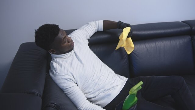 Exhausted african american black man resting on the couch after cleaning appartment. High quality photo