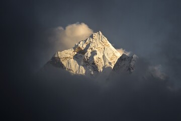 Amazing shot of Ama Dablam mountain peak (6812m) covered with white snow and surrounded with light clouds. Nepalese Himalayas.