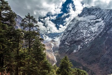 Great landscape of Himalaya mountains, mountain river, great cloudscape and coniferous forest on the foreground. Nepal.