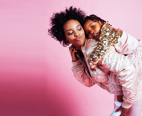 young pretty african-american mother with little cute daughter hugging, happy smiling on pink background, lifestyle modern people concept
