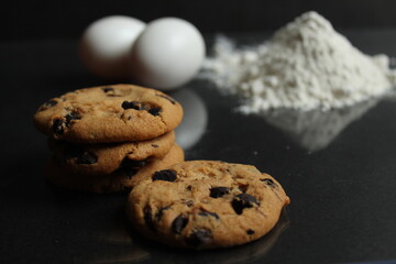 kitchen still life cooking process homemade chocolate cookies with chocolate drops in the background flour and chicken eggs lie on a black mirror background with a reflection of copy space
