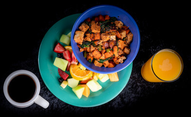 Image of a healthy breakfast with a tofu sweet potato scramble, fruit and orange juice.