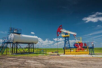 Fototapeta na wymiar ULYANOVSK, RUSSIA - JUNE 30, 2017: Oil pump at oil field in Ulyanovsk region. Summer. Bright blue sky with white clouds.