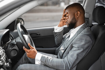 Black businessman having troubles at work, sitting in car