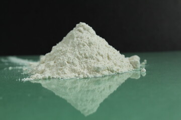 white flour of the highest or first grade lies in a heap on a black and green mirror background with a reflection side view there is a copy space