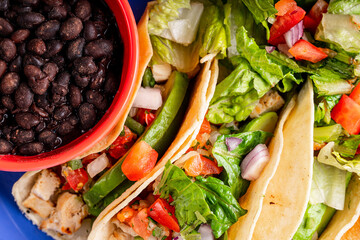 A delicious plate of tacos with a flavorful beverage, beans and salad.