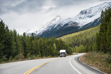 Road trip of Camper van driving on highway with rocky mountains in pine forest at Banff national park