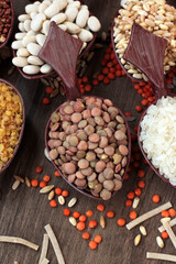 Uncooked dry cereal food group in wooden spoons on wooden surface with autumn leaves.Selected green lentil spoon