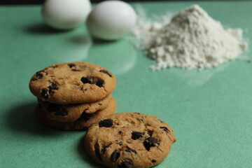 kitchen still life cooking process homemade chocolate cookies with chocolate drops in the background flour and chicken eggs lie on a green grass mirror background with a reflection of copy space