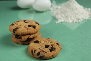 kitchen still life cooking process homemade chocolate cookies with chocolate drops in the background flour and chicken eggs lie on a green grass mirror background with a reflection of copy space