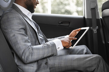 Unrecognizable black man manager using digital tablet in car