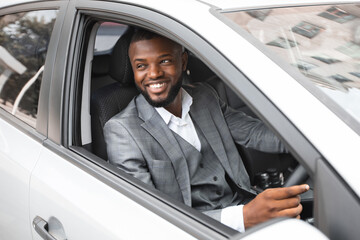 Handsome happy african american businessman driving luxury car