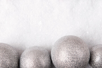 Festive Christmas background with silver baubles on snow