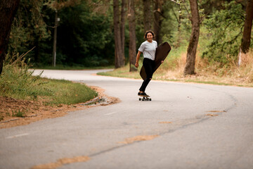 happy smiling woman rides on skateboard with wakeboard in her hand