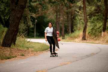 attractive woman rides on skateboard with wakeboard in her hand