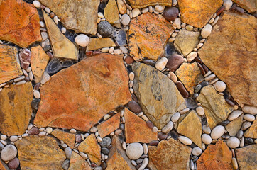 Floor, wall of brown and beige stones laid in a geometric pattern, floor with cracks