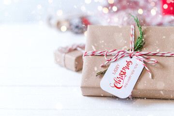 Merry Christmas and happy new year eco gift with tag and spruce branch. Glowing snow bokeh. Winter...