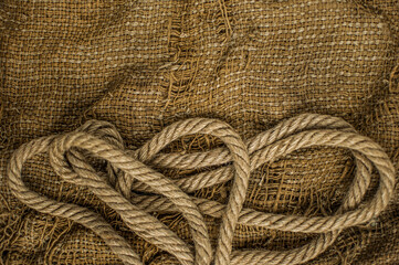 Hemp rope on burlap. Close-up of a natural rope and fabric. Calm nice background. Top view