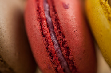 Colorful macaroons, delicious French pastries, stacked on wooden table.