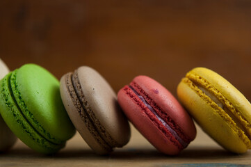 Colorful macaroons, delicious French pastries, stacked on wooden table.