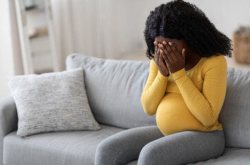 Young pregnant woman feeling sad and crying at home