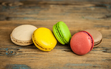 Colorful macaroons, delicious French pastries, stacked on wooden table.