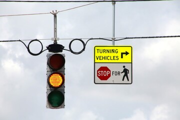 Yellow Traffic Light next to Turning Vehicles arrow right Stop for Pedestrians sign overhanging the...