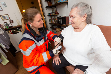 a paramedic measures an old woman's blood pressure