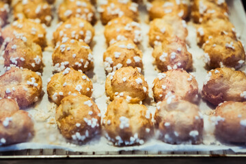 Choux à la crème dorés avec des morceaux de sucre sur la plaque du four