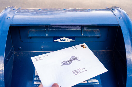 Close up placing an absentee election ballot into mailbox