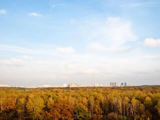 Obraz premium blue sky with white clouds over town and colorful forest on autumn afternoon