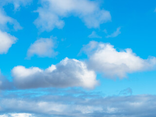 low fluffy cumulus clouds in blue sky on sunny autumn day