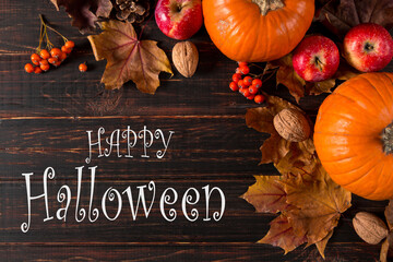 Pumpkin, fallen leaves, apples and berries, the inscription of a happy halloween. The concept of a holiday greeting card.