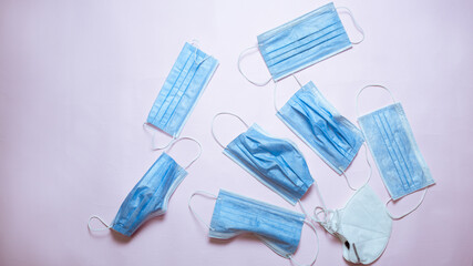 Used medical face masks over pink background, top view. Environmental pollution concept	