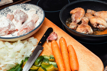 vegetables and chicken thighs fried in a frying pan . preparing the meal