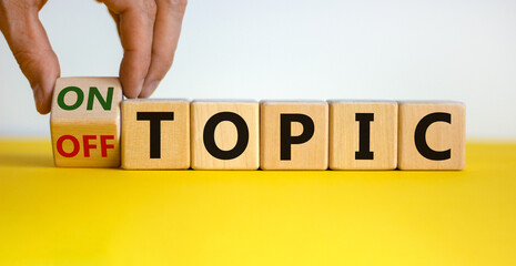 Hand turns a cube and changes the expression 'off topic' to 'on topic'. Beautiful yellow table, white background. Business concept. Copy space.