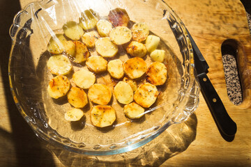 sliced potatoes in a glass dish covered by a plastic ready to cook heat in a microwave