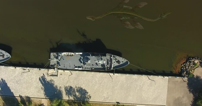 Aerial view in muddy water: Dragon, monster of prehistoric era, floats underwater along the pier where two military boats are moored, torpedo. Ness Monster