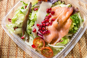 healthy green salad with smoked fish and pomegranate to go