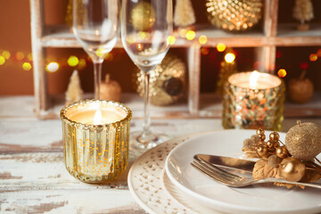 Festive table setting for Christmas holiday celebration with plate, candle and decorations.