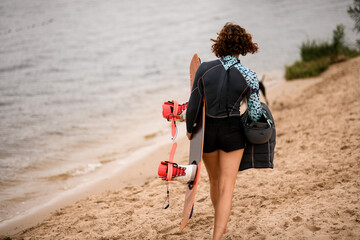 rear view of woman walking along the river bank with wakeboard
