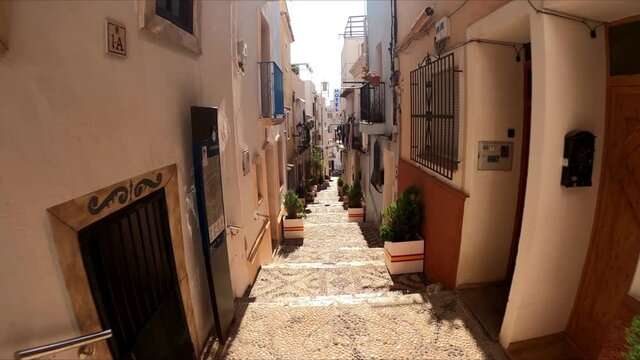 Calpe main street walking POV by Calp streets in Alicante, Spain, while bell tower rings. 
