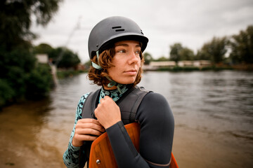 portrait of attractive woman in helmet and vest who stands on the river bank