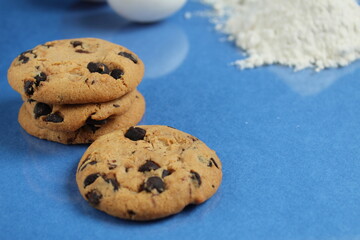 kitchen cooking process homemade chocolate cookies with chocolate drops in the background flour and chicken eggs lie on a blue bright rich mirror background side view with a reflection of copy space