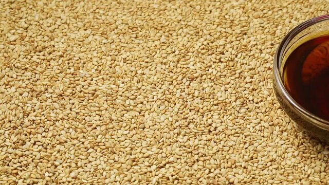 Sesame seeds full frame and a glass bowl with brown sesame oil