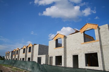 Townhomes under construction in a hot sunny afternoon protected by a green fence