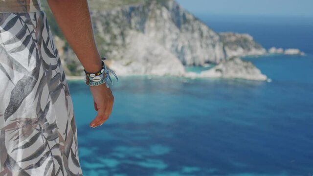 Woman hand with wristband enjoying vacation travel adventure. Mountain coast, beautiful sea bay scenic landscape in background
